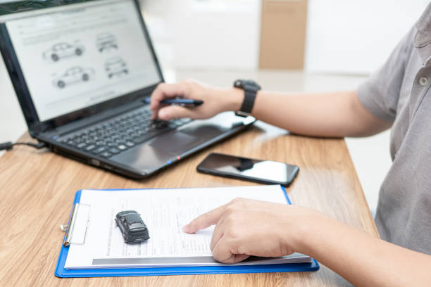 Pessoa digitando no notebook dados de um documento em papel A4, simbolizando atualização cadastral de veículo.