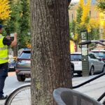Agente de trânsito aplicando multa a veículo parado em local proibido.