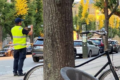 Agente de trânsito aplicando multa a veículo parado em local proibido.