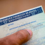 Homem segurando a Carteira Nacional de Habilitação (CNH), documento que comprova que ele está autorizado a conduzir veículos no Brasil.”