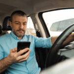 Motorista consultando a data de vencimento da CNH pelo celular antes de iniciar o processo de renovação online.