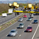 Veículos circulando na rodovia com um radar de fiscalização de velocidade