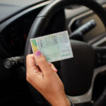 Pessoa mostrando CNH dentro do carro.