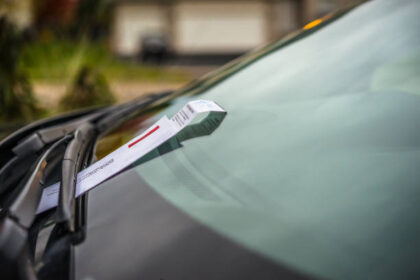 Veículo com um recibo de multa colocado no limpador de para-brisa.