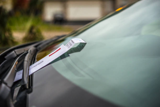 Veículo com um recibo de multa colocado no limpador de para-brisa.